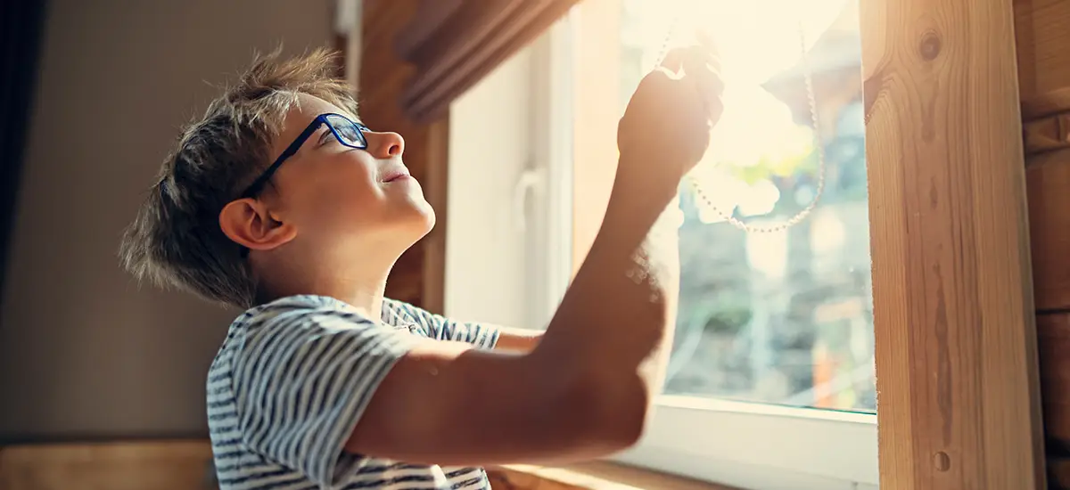 Boy lowering the blinds